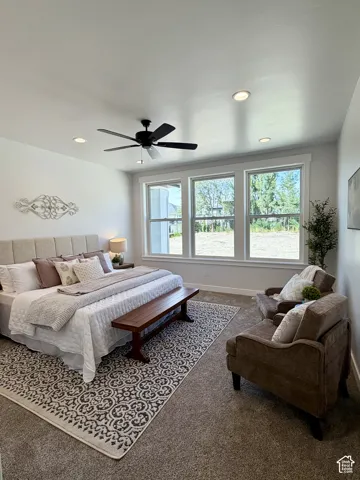 Recessed ceiling lighting, ceiling fan, multiple large windows, wall-to-wall carpeting, and an upholstered headboard
