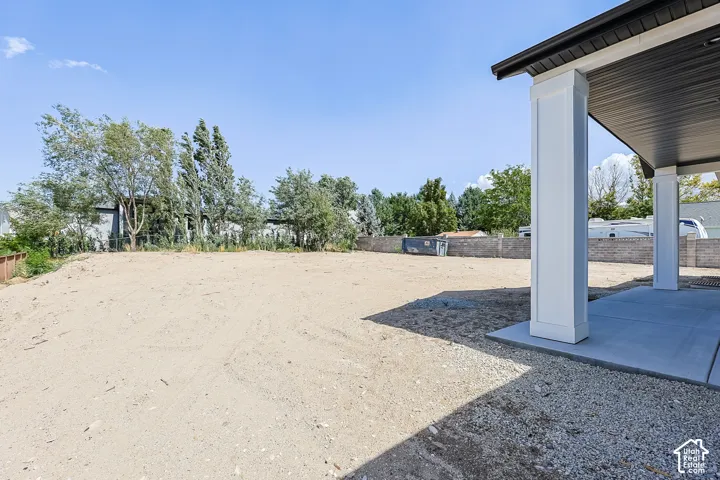 Expansive rear yard space with a covered patio area, solid concrete slab, and structural support columns