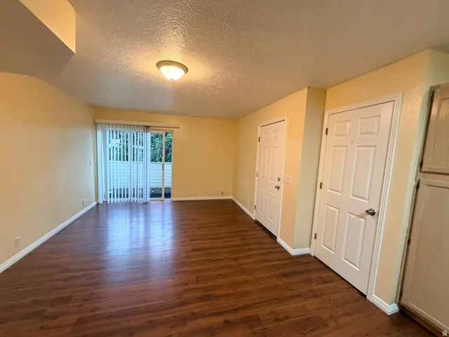 Wood-finish flooring, sliding glass door with vertical blinds, built-in overhead light fixture, and paneled interior doors
