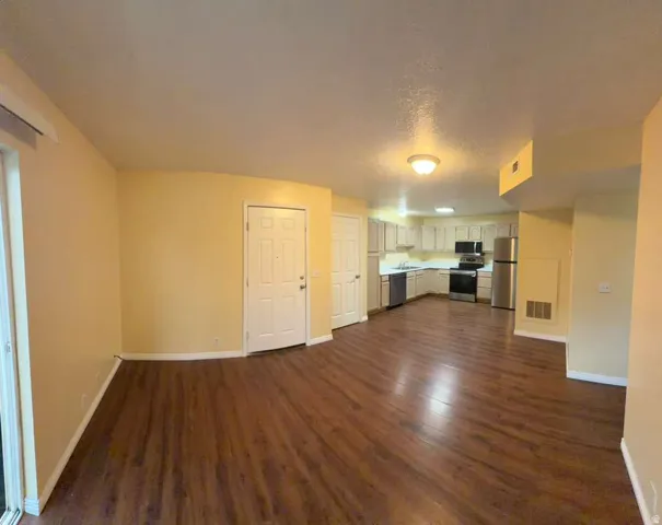 Open-concept living area featuring wood-finish flooring, recessed lighting, and a full kitchen with stainless steel appliances
