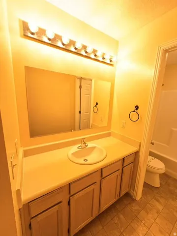 Vanity with integrated sink, wood-finish cabinetry, and overhead lighting fixture