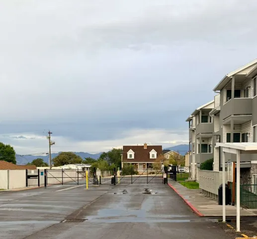 Asphalt driveway with gated entry and multi-level residential building exterior