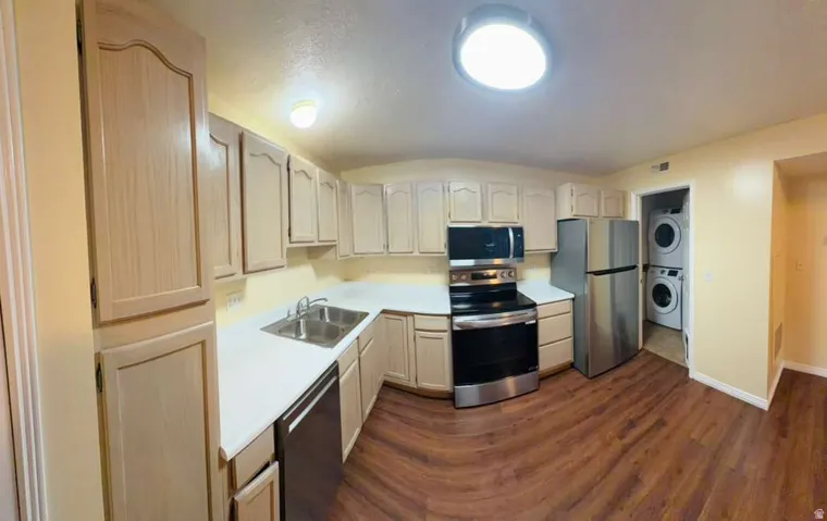 Kitchen featuring wood-finish cabinetry, stainless steel appliances, a double basin sink, and white countertops