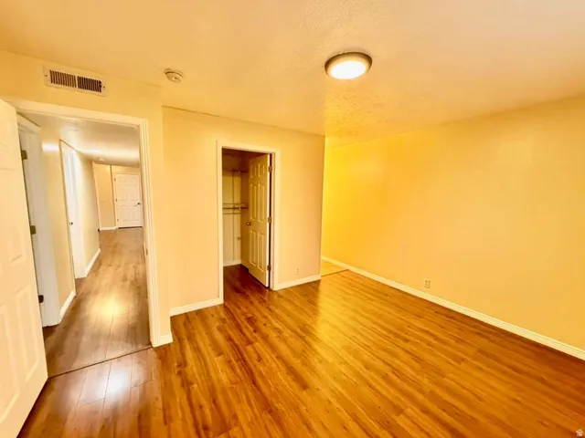 Wood-finish flooring throughout, recessed ceiling light fixture, and a built-in closet with shelving and hanging rods