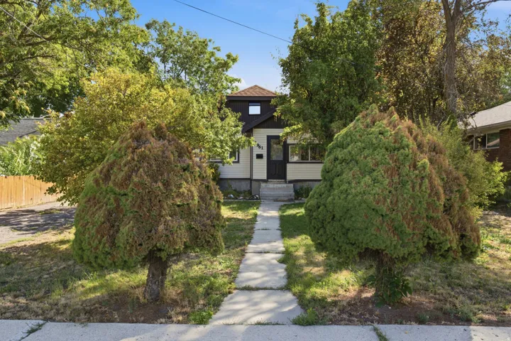 Light-toned horizontal siding with dark trim accents, a front entry with a dark door, and a concrete pathway