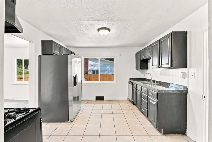 Kitchen featuring tile flooring, dark cabinetry, and white appliances