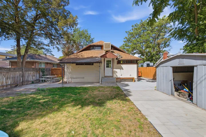 Private backyard featuring mature trees, a detached storage shed, a paved driveway, and a fenced perimeter