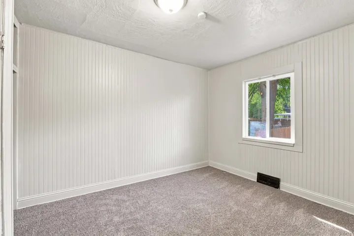 Wall-to-wall carpet flooring, white beadboard walls, single window with white trim, and a ceiling-mounted light fixture