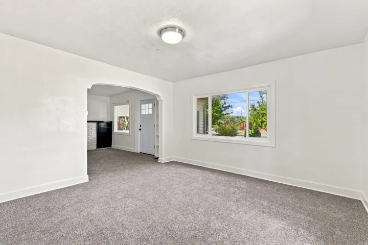 White painted walls, grey carpeting, and a window with white trim