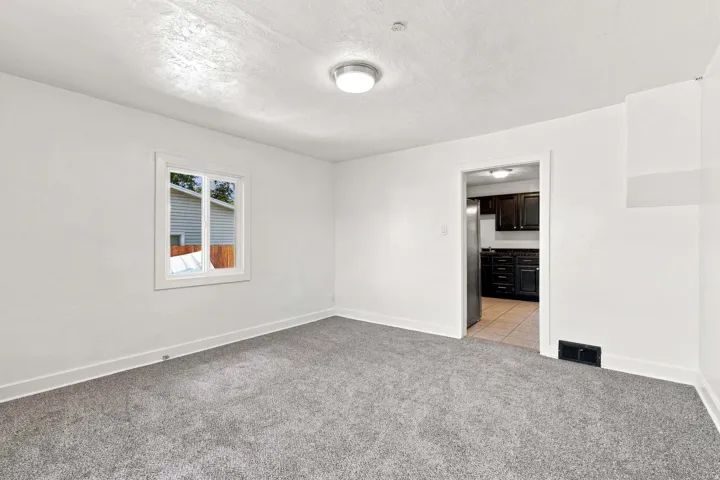 Recessed ceiling lighting illuminates a room featuring light-colored walls and plush carpeting