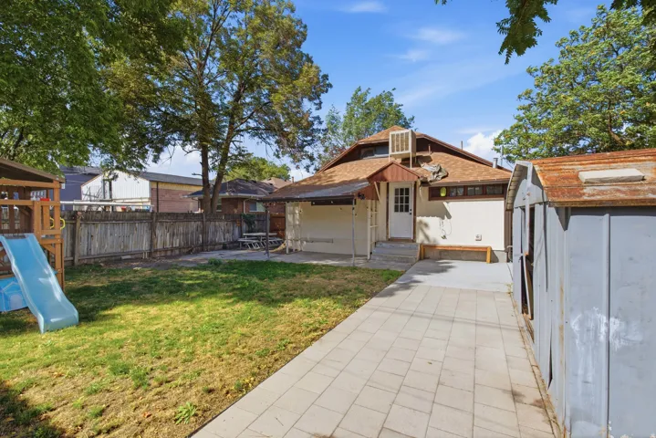 Expansive backyard featuring a paved path, mature trees, and a privacy fence