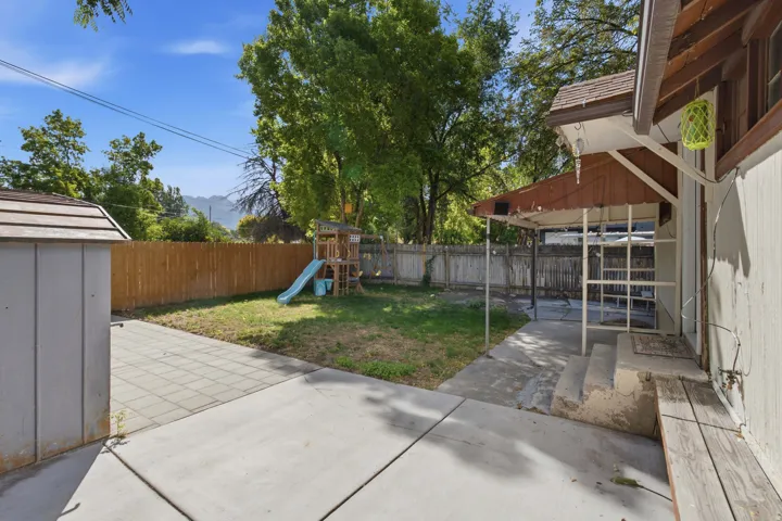 Backyard featuring a covered patio, concrete and paver hardscaping, wood privacy fencing, and mature trees