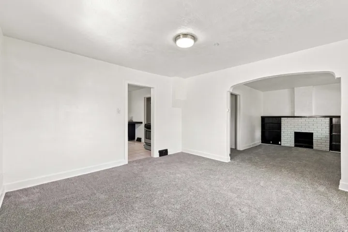 Carpeted living area with a white brick fireplace, built-in shelving, and a cased opening