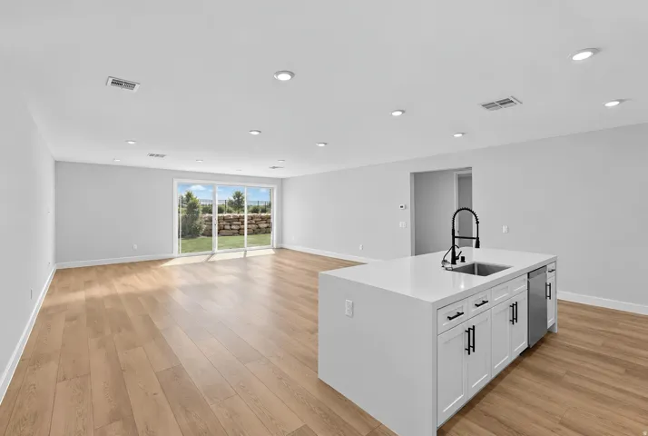 Recessed lighting, wood-finish flooring, sliding glass patio door, kitchen island with built-in sink, and dishwasher