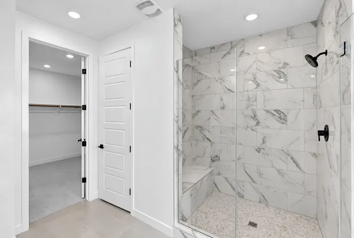 Walk-in shower with clear glass enclosure, a built-in bench, and black fixtures