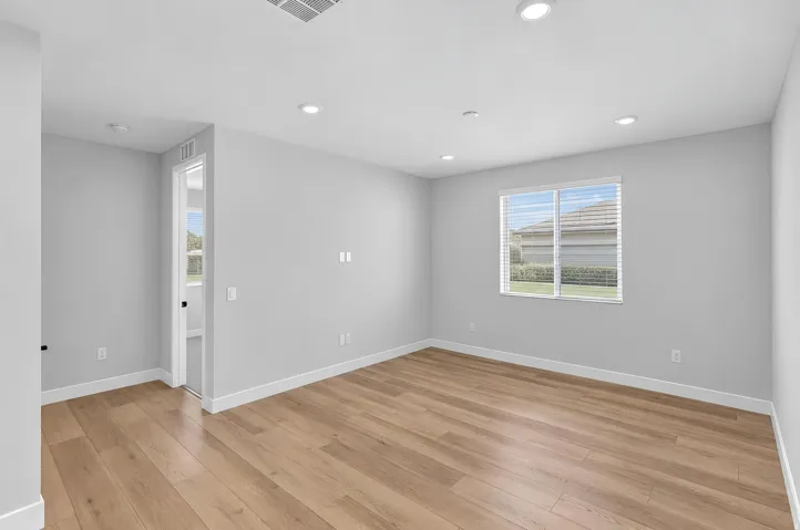 Recessed ceiling lighting, wood-finish flooring, and a large window with blinds