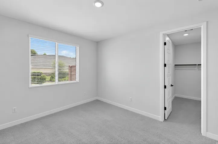 Recessed ceiling lighting, light gray wall paint, gray carpet flooring, white window blinds, and white paneled door with dark hardware