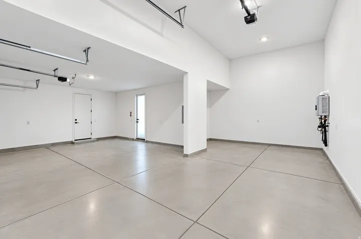 Spacious garage with concrete flooring, recessed lighting, white walls, and a tankless water heater