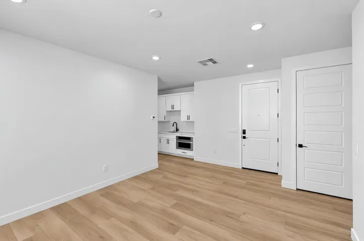 Wood-finish flooring throughout, recessed ceiling lighting, and white interior doors
