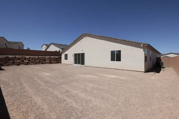 Expansive gravel lot featuring a rock retaining wall and stucco exterior