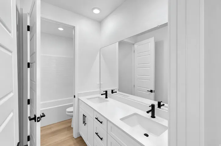 Dual vanity with undermount sinks, single-handle matte black faucets, and a full-width mirror