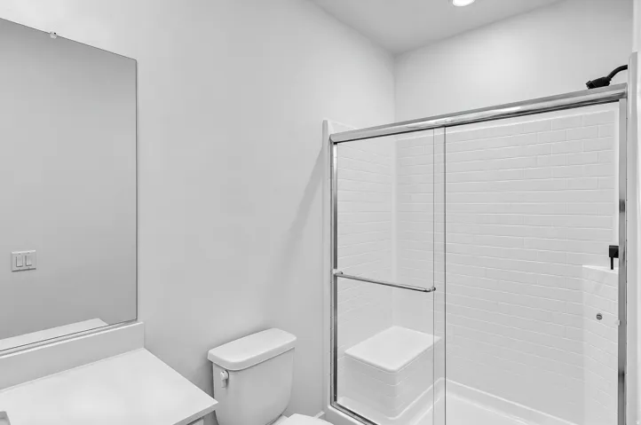 Shower with subway tile surround, sliding glass door, and integrated seating