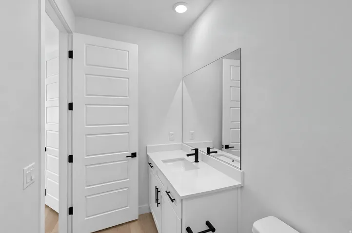 Modern bathroom vanity with white countertop, integrated sink, and matte black fixtures
