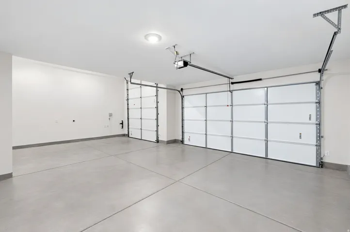Spacious garage with light grey concrete flooring and two overhead garage doors