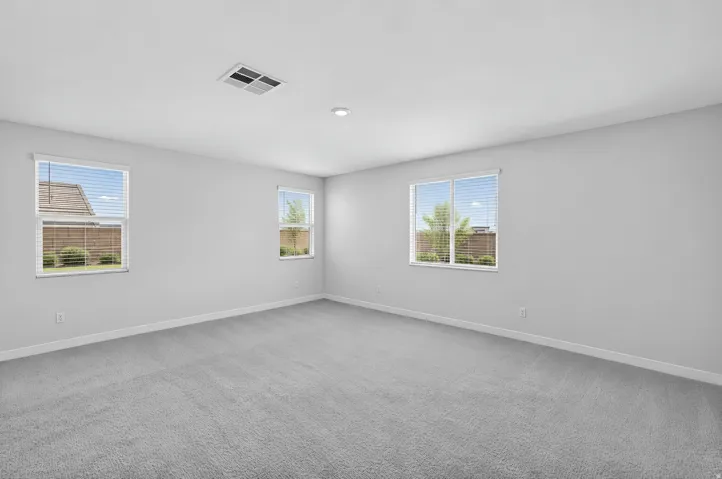 Expansive room featuring light gray carpeting, multiple windows with blinds, recessed lighting, and a ceiling vent