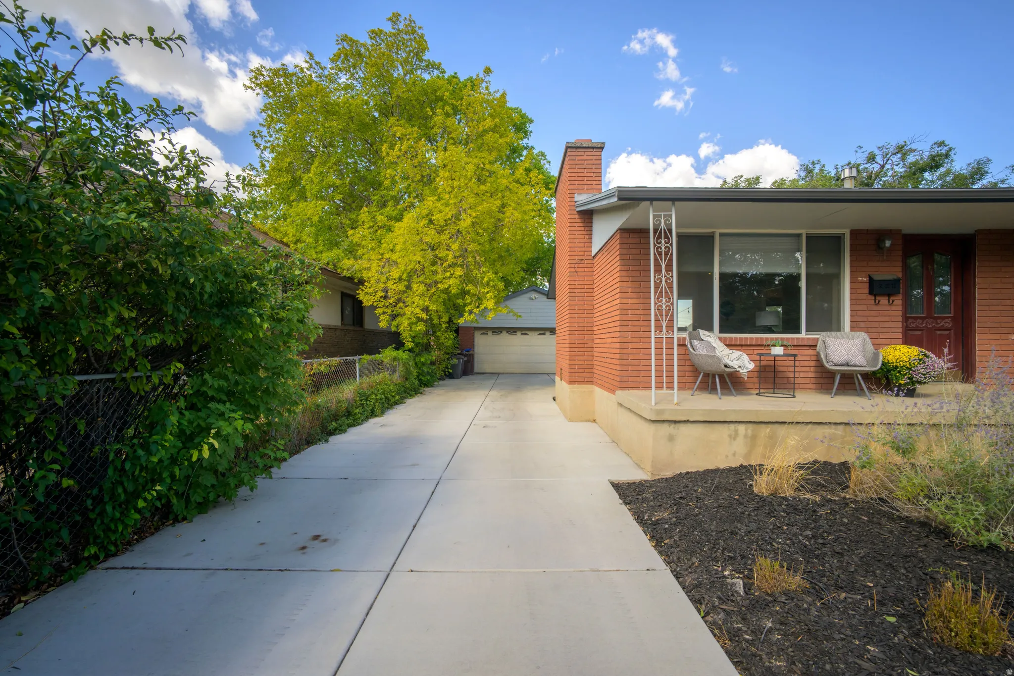 Brick exterior with a prominent chimney, covered front porch, and expansive concrete driveway