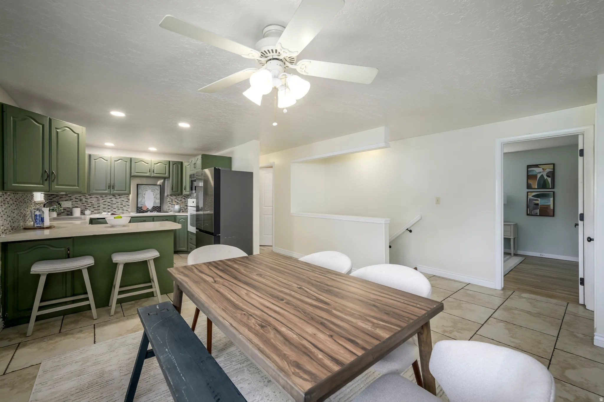 Kitchen featuring green cabinetry, light-toned countertops, and a mosaic tile backsplash