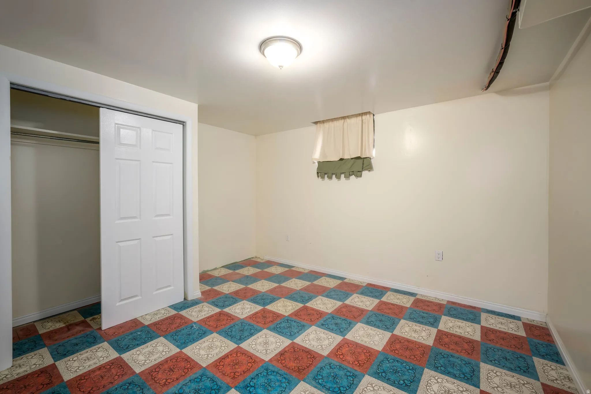 Recessed window, ceiling-mounted light fixture, white walls, and a patterned floor