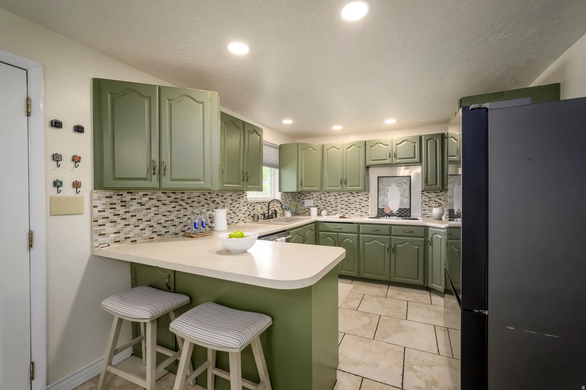 Kitchen featuring ample cabinetry, mosaic tile backsplash, solid surface countertops, and tile flooring