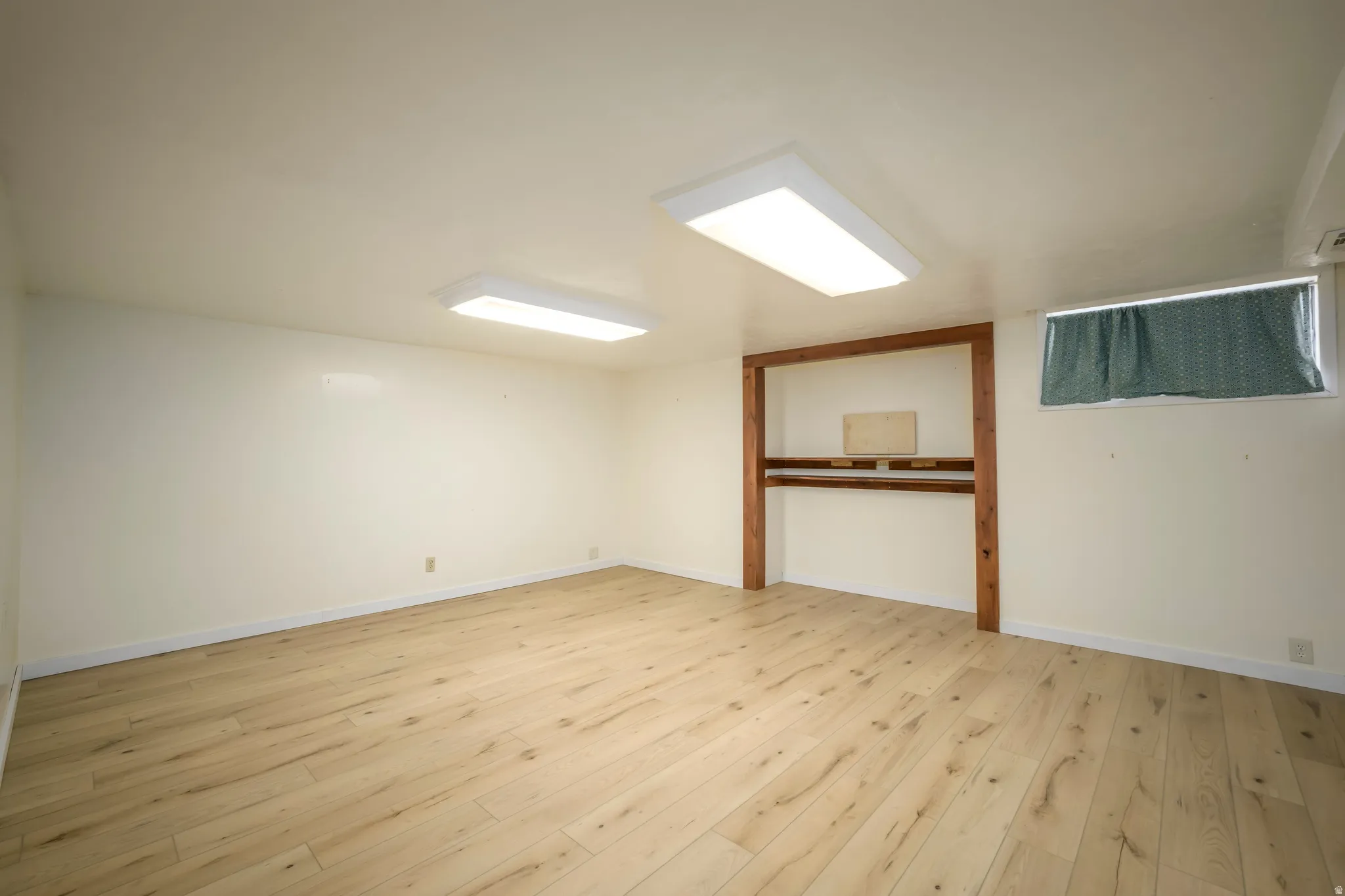 Light wood-finish flooring, recessed lighting, and a built-in wooden shelving unit