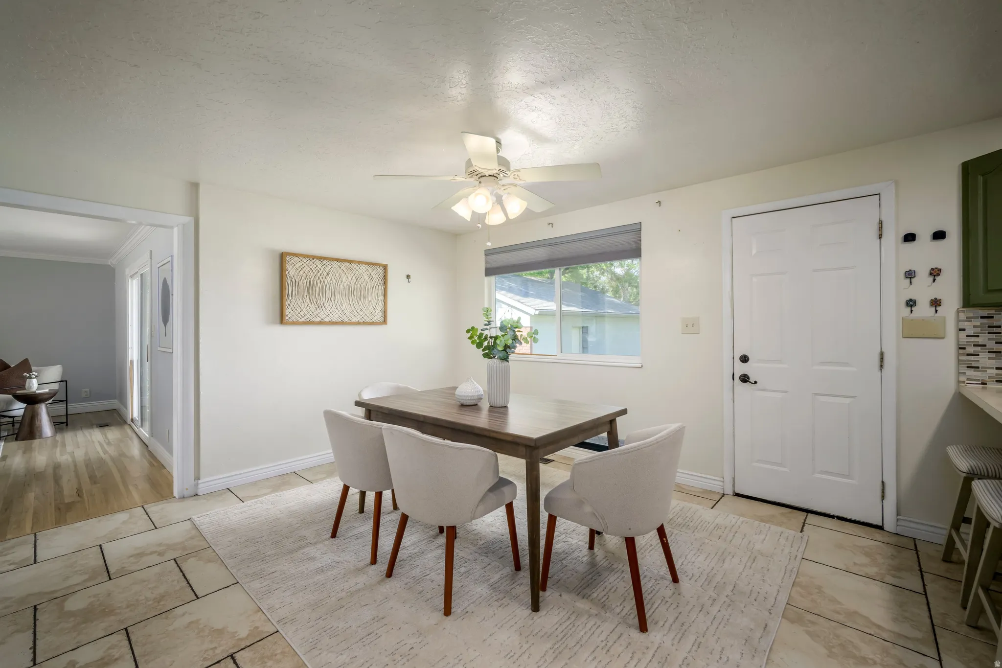 Tile flooring, white paneled door, window with roller shade, ceiling fan