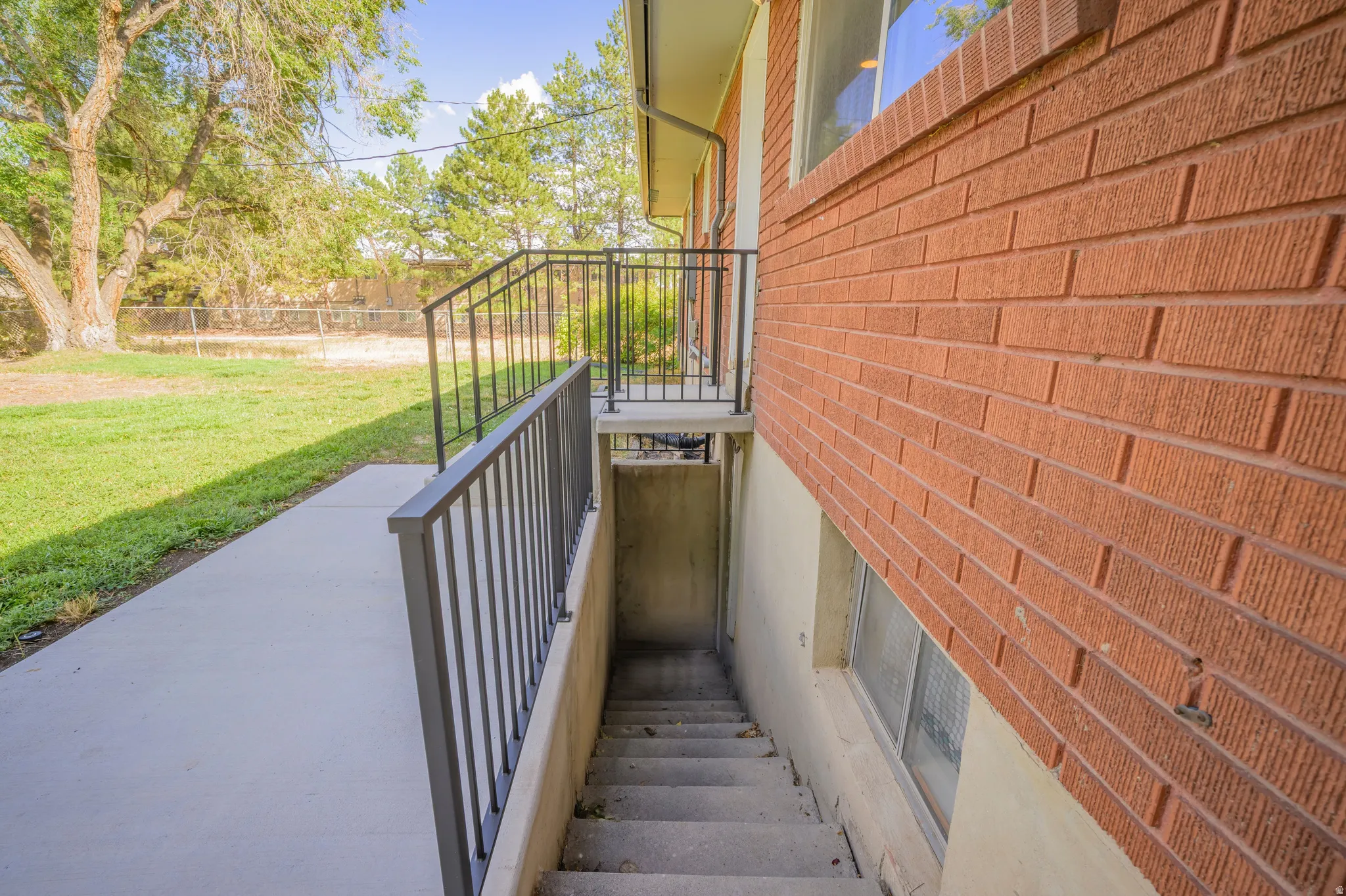 Red brick exterior with a concrete walkway and dark metal railings
