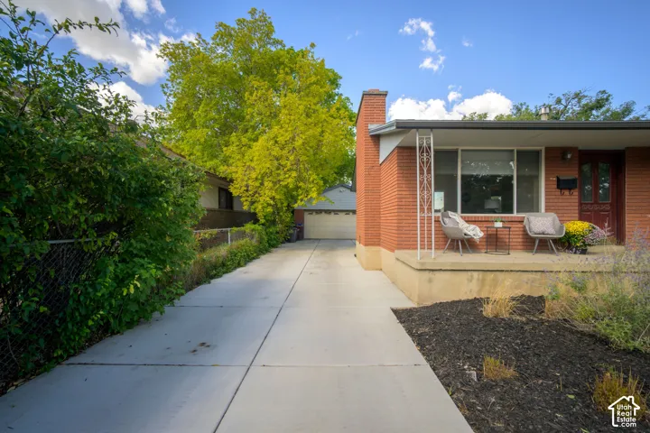 Brick exterior with a prominent chimney, covered front porch, and expansive concrete driveway