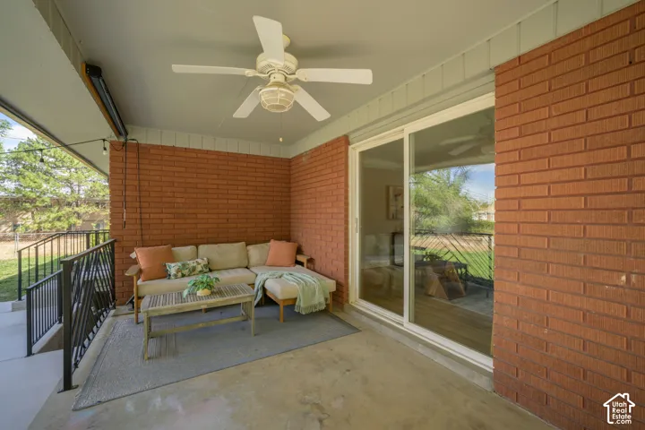 Covered patio with a ceiling fan, brick wall, and sliding glass door