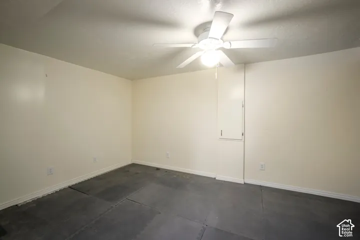 Neutral painted walls with a ceiling fan light fixture and gray flooring
