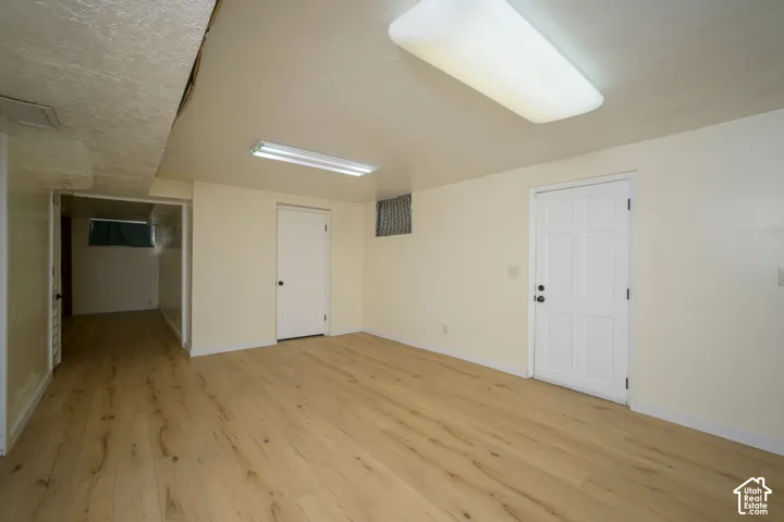 Finished room featuring wood-finish flooring, white paneled doors, and overhead fluorescent lighting