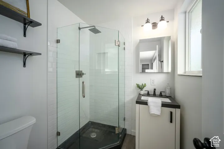 Corner glass-enclosed shower with subway tile surround and dark-finish shower pan