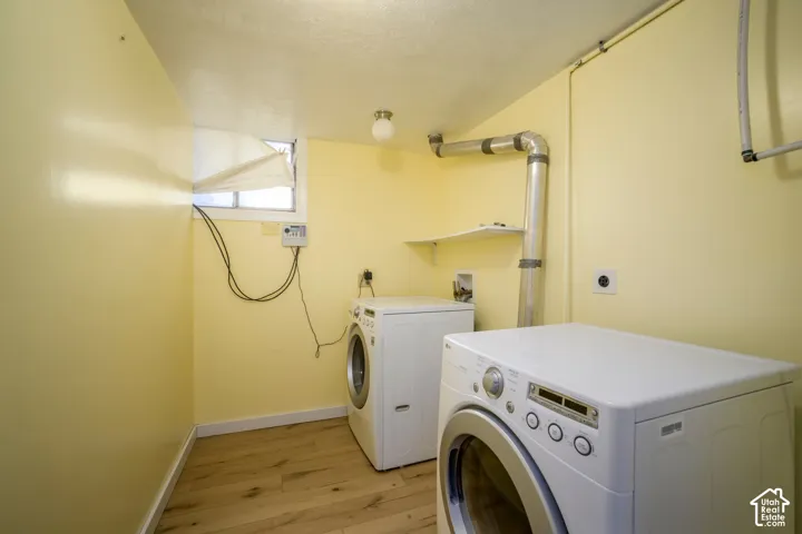 Laundry area featuring wood-finish flooring, a wall-mounted shelf, and a ceiling-mounted light fixture