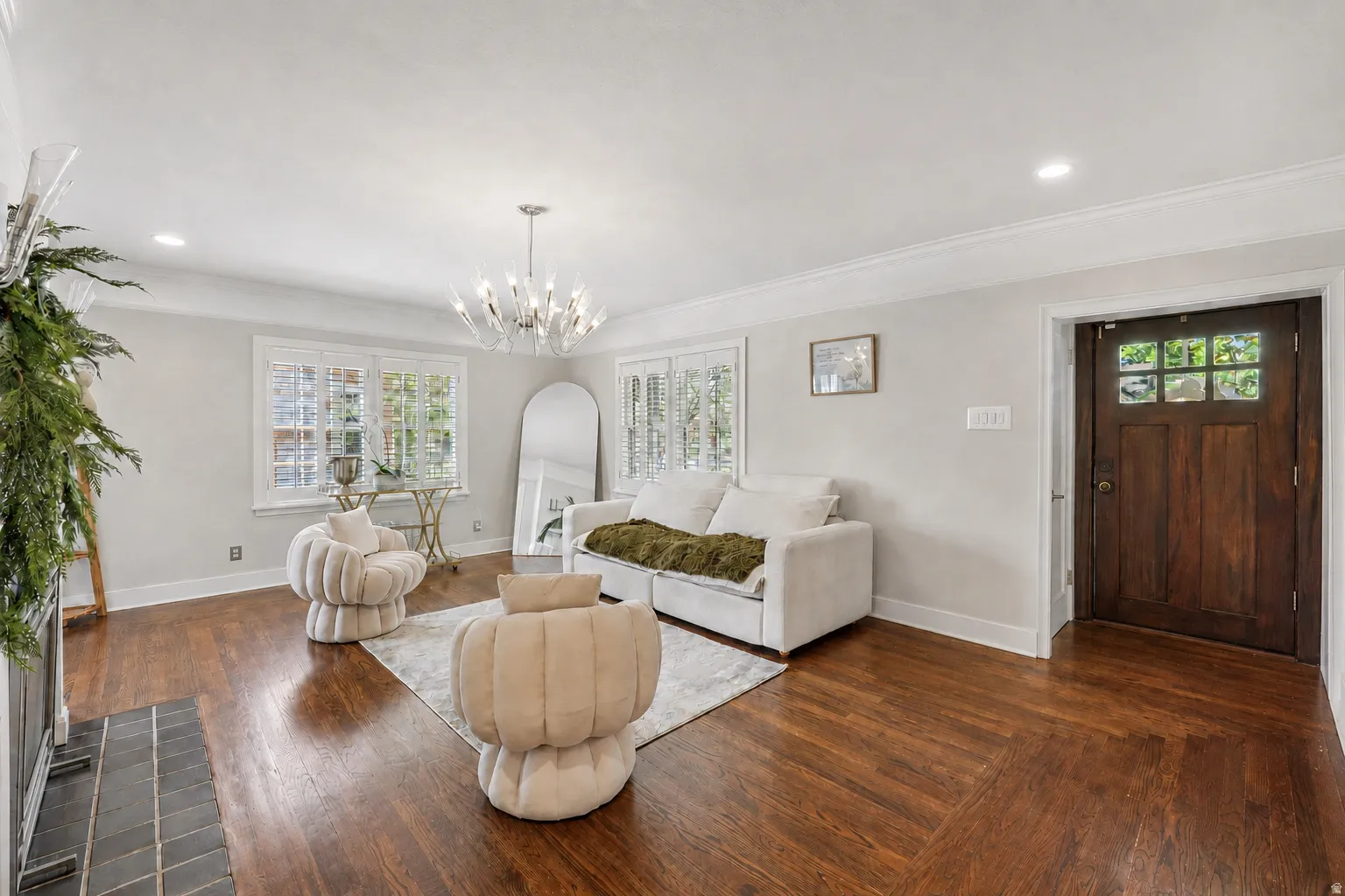 Hardwood flooring with a herringbone pattern, crown molding, a wood-paneled entry door with glass inserts, recessed lighting, and a modern chandelier