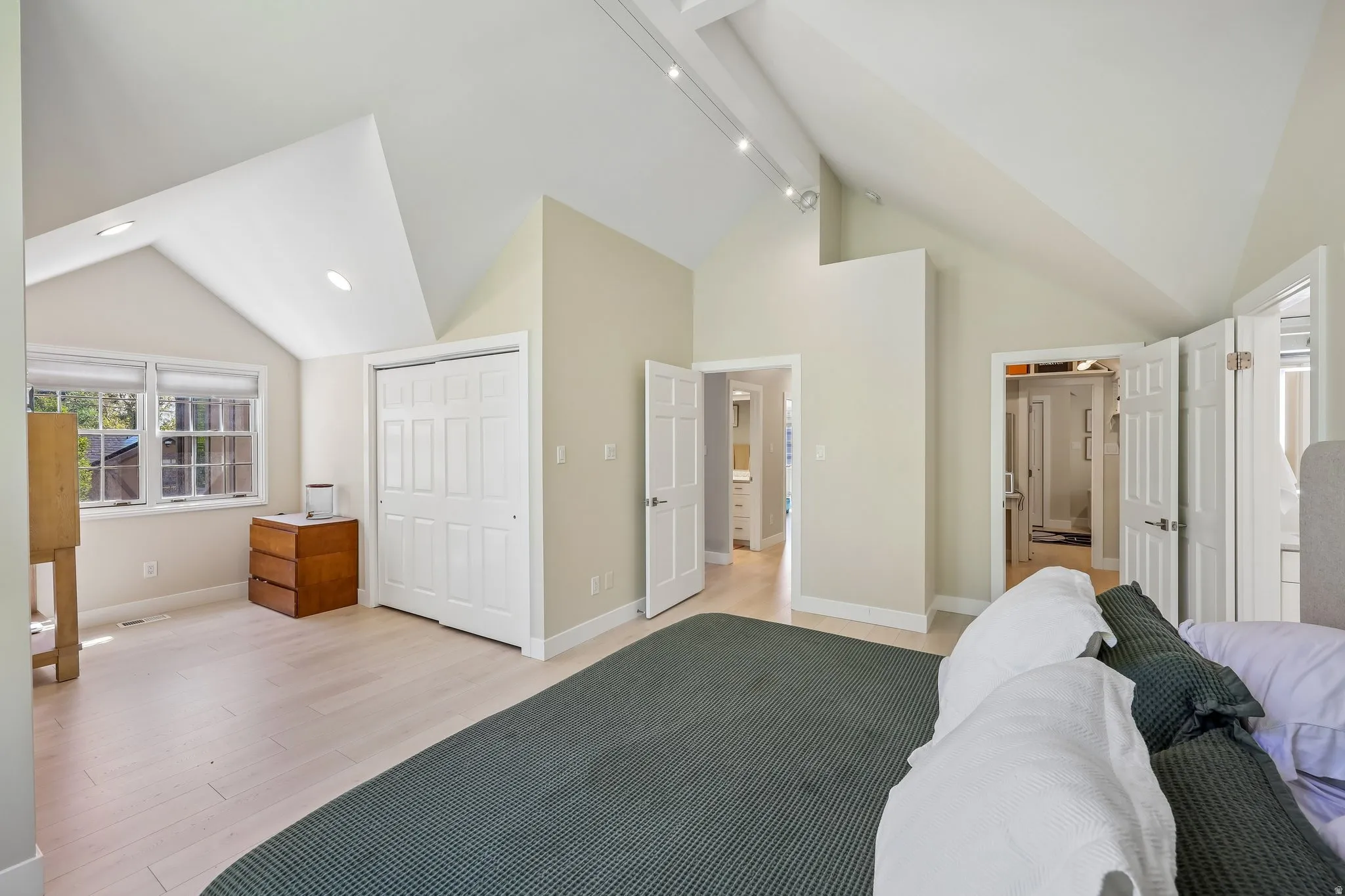 Vaulted ceiling with recessed lighting, light wood-finish flooring, and white paneled doors