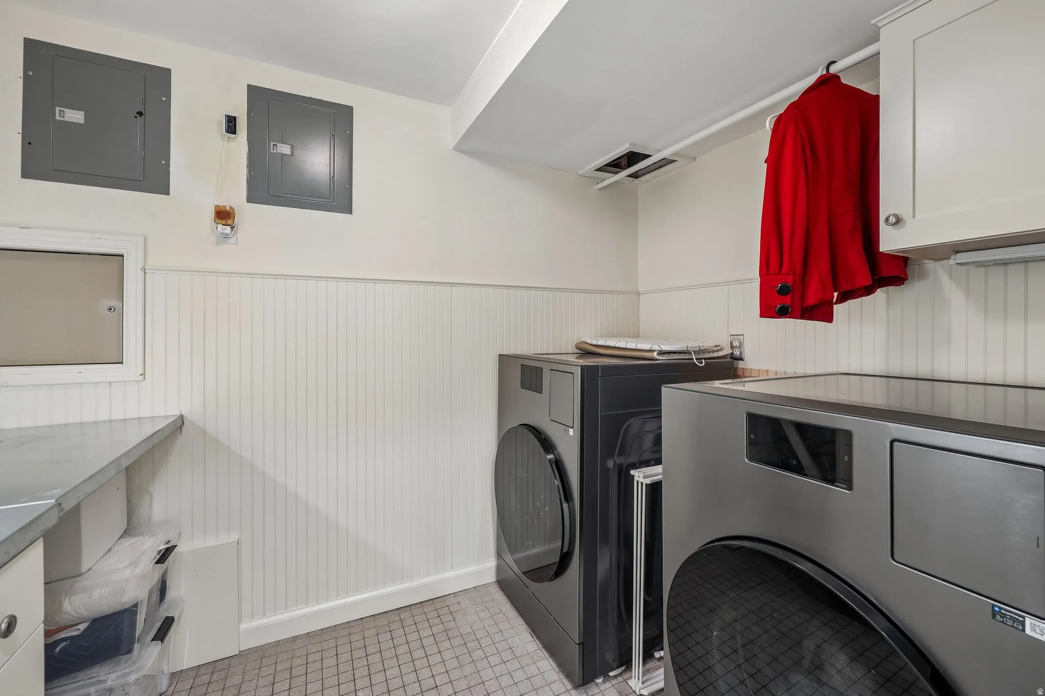 Laundry area featuring beadboard wainscoting, a utility countertop, overhead cabinetry, and tiled flooring