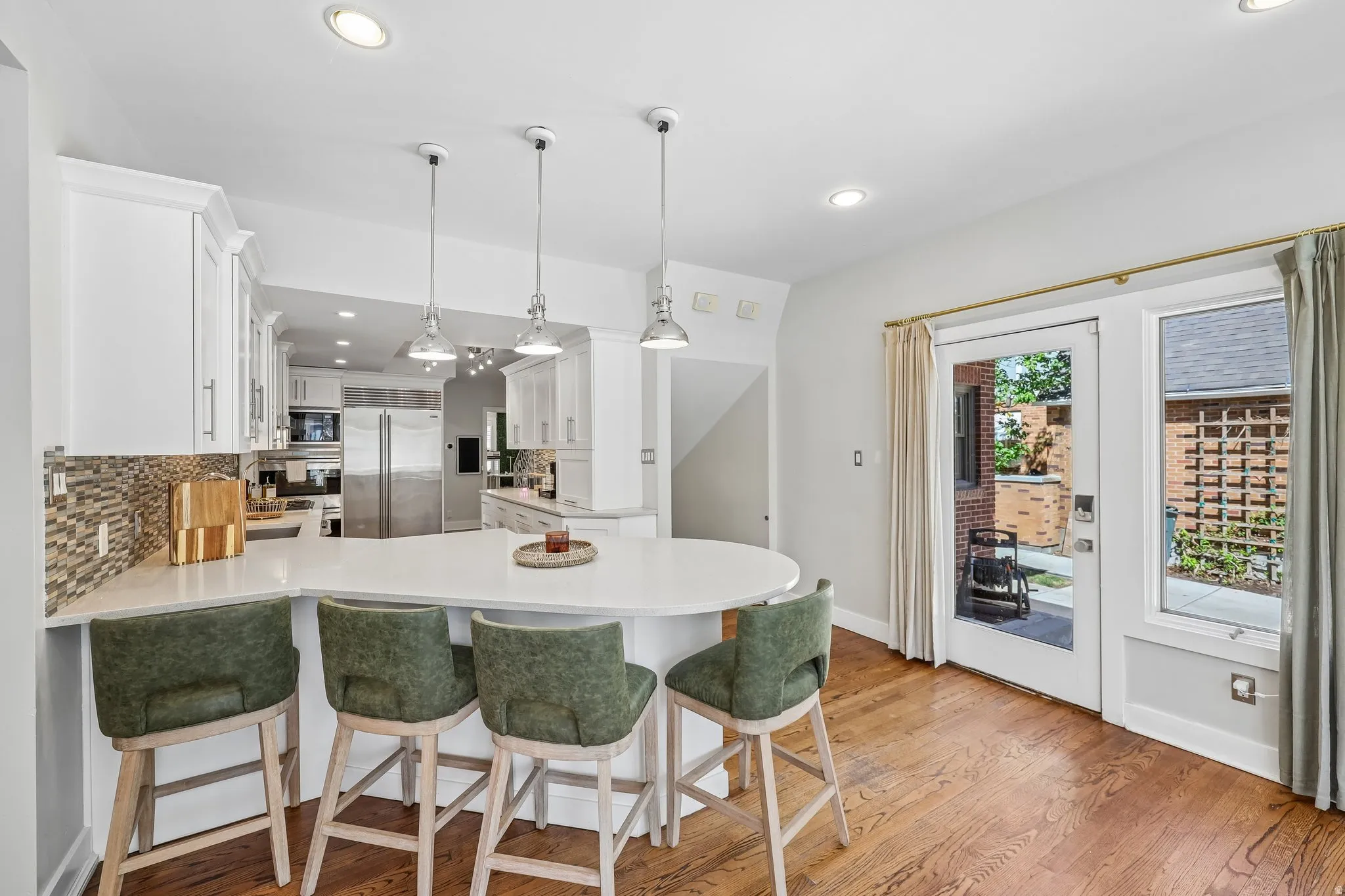 White kitchen cabinetry with mosaic tile backsplash and a kitchen island with seating