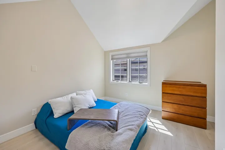 Bright room with an angled ceiling, light wood-finish flooring, and a double-pane window