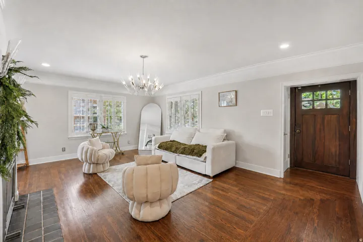 Hardwood flooring with a herringbone pattern, crown molding, a wood-paneled entry door with glass inserts, recessed lighting, and a modern chandelier