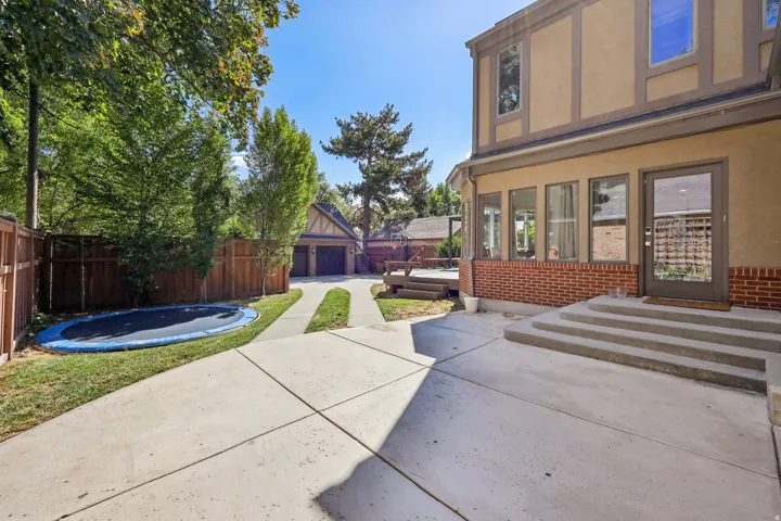 Two-story exterior with stucco and brick facade, concrete patio, and mature trees