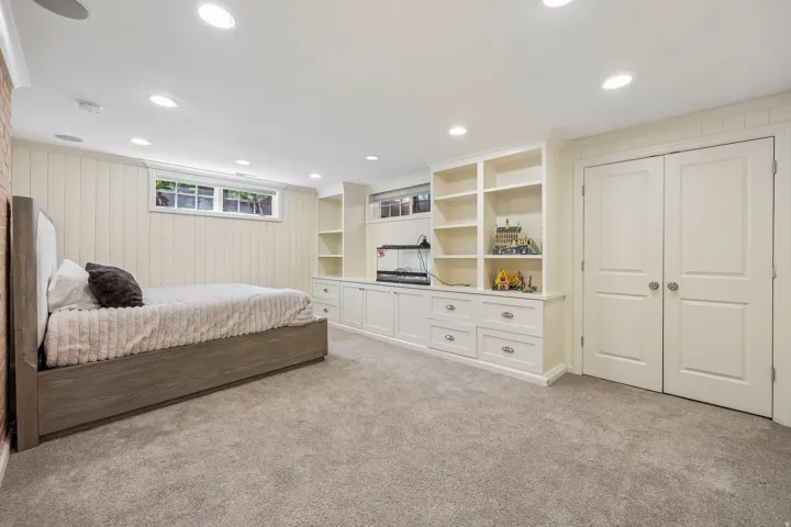 Wall-to-wall carpeting, recessed ceiling lighting, built-in cabinetry with shelving and drawers, two-panel interior doors, and a horizontal window